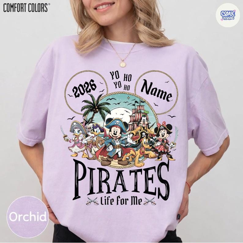 May include: Orchid-colored t-shirt with a pirate-themed graphic featuring Mickey Mouse and friends. The design includes the text "2026", "Yo Ho", "Name", and "Pirates Life for Me". The shirt has the "Comfort Colors" logo.