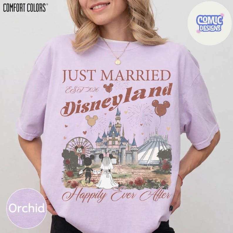 May include: Orchid-colored t-shirt with a Disneyland graphic. The design includes the text "Just Married Disneyland Est 2026" with Mickey and Minnie Mouse, a castle, and the words "Happily Ever After".
