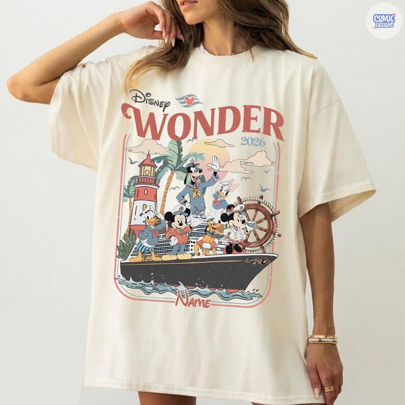 Puede incluir: Camiseta color crema con un gr&aacute;fico del crucero Disney Wonder con Mickey Mouse, Donald Duck y otros personajes. El dise&ntilde;o incluye el texto "Disney Wonder 2026" en rojo y un faro.