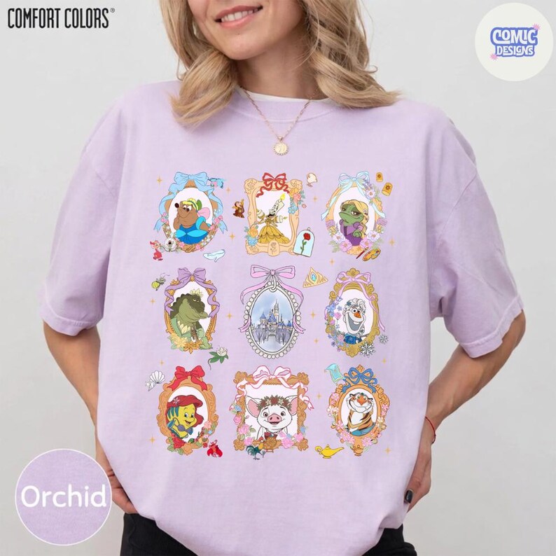 Puede incluir: Camiseta color orqu&iacute;dea con una colecci&oacute;n de retratos enmarcados de personajes de dibujos animados. Los retratos est&aacute;n en marcos ornamentados con lazos y detalles florales. La camiseta tiene los logotipos "COMFORT COLORS" y "COMIC DESIGNS".