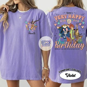 Puede incluir: Camiseta violeta Comfort Colors con una gacela de dibujos animados y la palabra "Auntie" en la parte delantera. La parte trasera muestra "Very Happy Birthday" con personajes de dibujos animados y el texto "Wishing you a year filled with joy and great memories."