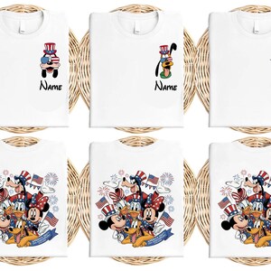 May include: White t-shirts featuring patriotic Disney characters. Designs include Goofy, Donald Duck, Mickey and Minnie Mouse, and Daisy Duck, all wearing patriotic attire. The word "Name" is printed below some characters.