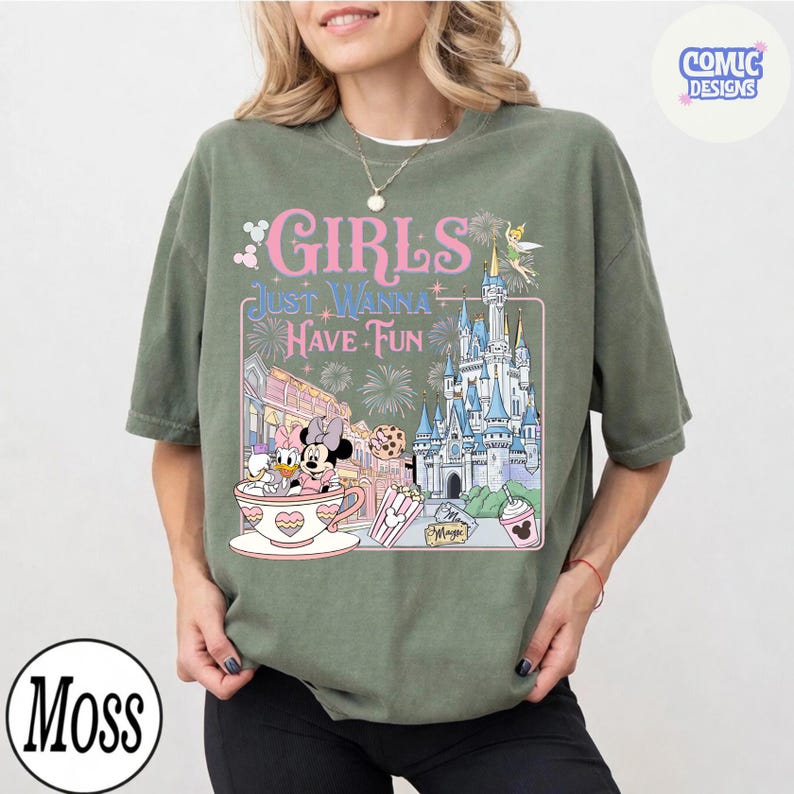 May include: Olive green t-shirt with the text "GIRLS JUST WANNA HAVE FUN" in pink and white. The graphic includes a castle, Minnie and Daisy Duck in a teacup, and other Disney-themed elements. A "Moss" logo is in the bottom left corner.