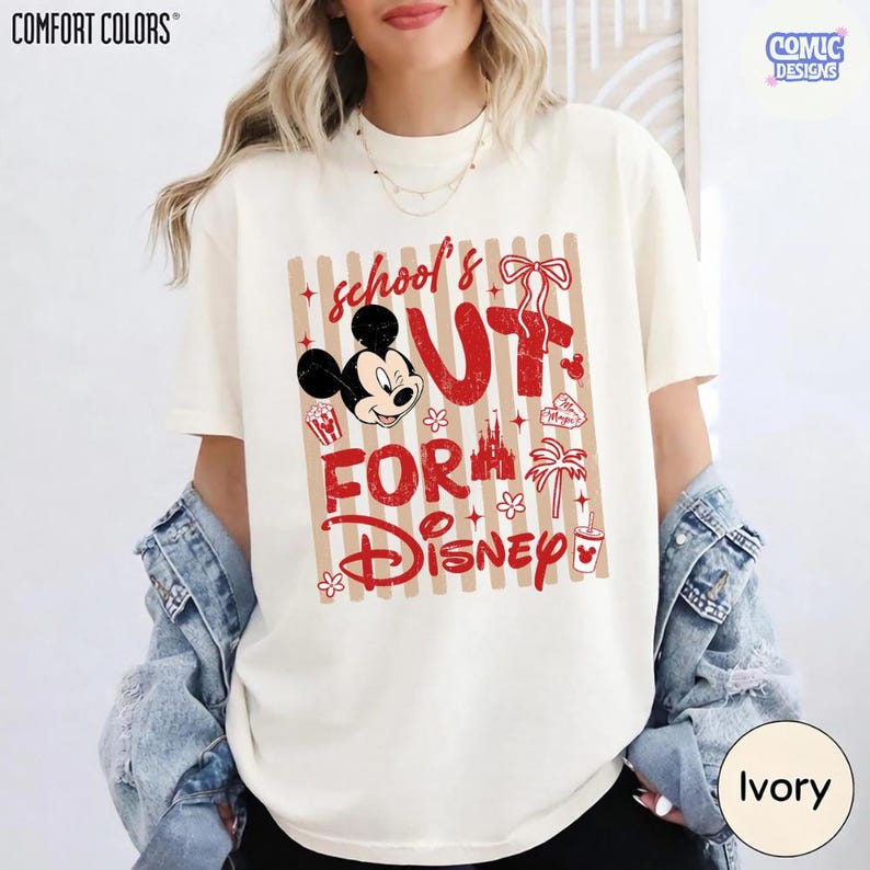 May include: Ivory-colored Comfort Colors t-shirt with a red and tan graphic. The graphic says "School's Out For Disney" with Mickey Mouse, popcorn, a castle, and a palm tree. The shirt has a crew neck and short sleeves.