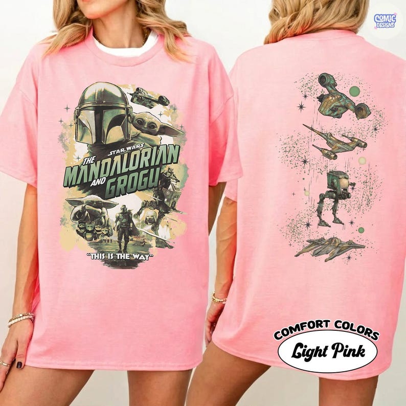 Op de afbeelding: Lichtroze T-shirt met een Star Wars-ontwerp met The Mandalorian en Grogu. De voorkant toont personages en tekst, terwijl de achterkant verschillende ruimtevaartuigen toont. Het shirt is gelabeld "COMFORT COLORS Light Pink."