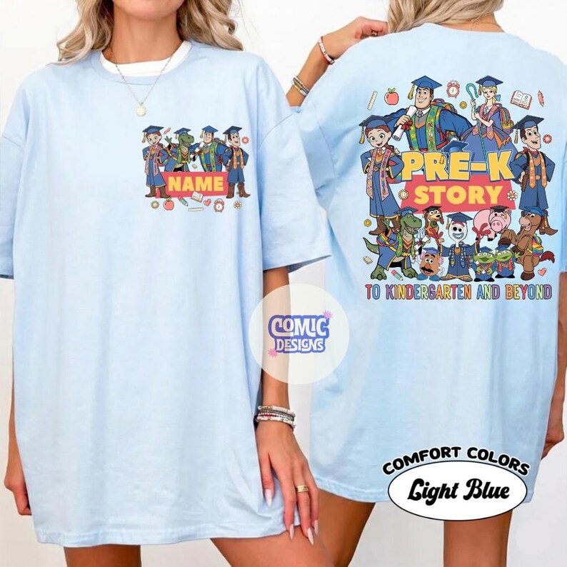 May include: Light blue t-shirt with a cartoon graphic featuring characters in graduation attire. The front of the shirt has the word "NAME" and the back says "PRE-K STORY TO KINDERGARTEN AND BEYOND". The shirt is labeled "COMFORT COLORS Light Blue".