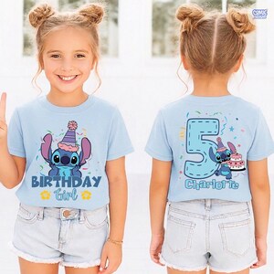 May include: Light blue t-shirt featuring a cartoon character with a party hat and the text "BIRTHDAY Girl". The back of the shirt displays a large number 5, the same character, a cake, and the name "Charlotte".