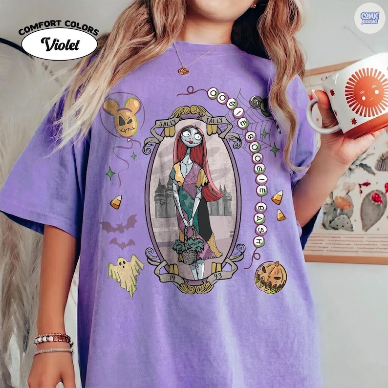 May include: A violet short-sleeve t-shirt featuring a graphic print of Sally from The Nightmare Before Christmas inside an oval frame. The design includes the text Oogie Boogie Bash, a ghost, bats, a pumpkin, and candy corn on a purple fabric.