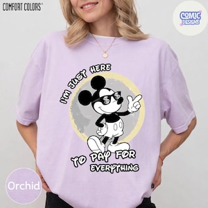 May include: Orchid-colored t-shirt with a graphic of Mickey Mouse wearing sunglasses with dollar signs. The text reads "I'M JUST HERE TO PAY FOR EVERYTHING". The shirt has the "COMFORT COLORS" and "COMIC DESIGNS" logos.