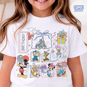May include: White t-shirt featuring a colorful birthday design with Disney characters like Mickey Mouse, Donald Duck, and Minnie Mouse. The design includes a castle, balloons, and the word "Birthday". The shirt is for a child's third birthday.