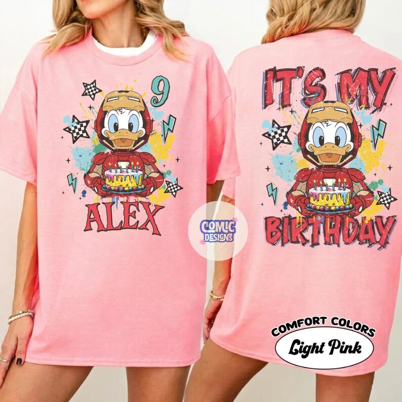 Puede incluir: Camiseta rosa claro con un dibujo de un pato con un casco de Iron Man y una tarta de cumplea&ntilde;os. La parte delantera de la camiseta dice "ALEX" y "9". La parte trasera dice "IT'S MY BIRTHDAY".