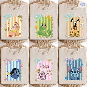 May include: Beige t-shirts featuring cartoon characters. Designs include a mouse with cheese, a green chameleon, Pluto the dog, Dory the fish, Piglet with a flower, and Stitch. Each design is framed with a ribbon and a striped background.