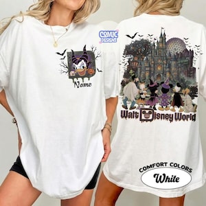 May include: A white t-shirt featuring a front graphic of Maleficent with the text Name and a back graphic of Disney characters in Halloween costumes in front of a castle with the text Walt Disney World and the Comic Designs logo.