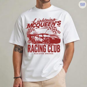 May include: White t-shirt featuring a red graphic of Lightning McQueen's Racing Club. The design includes a race car, checkered flags, and the text "Lightning McQueen's Racing Club, Radiator Springs".