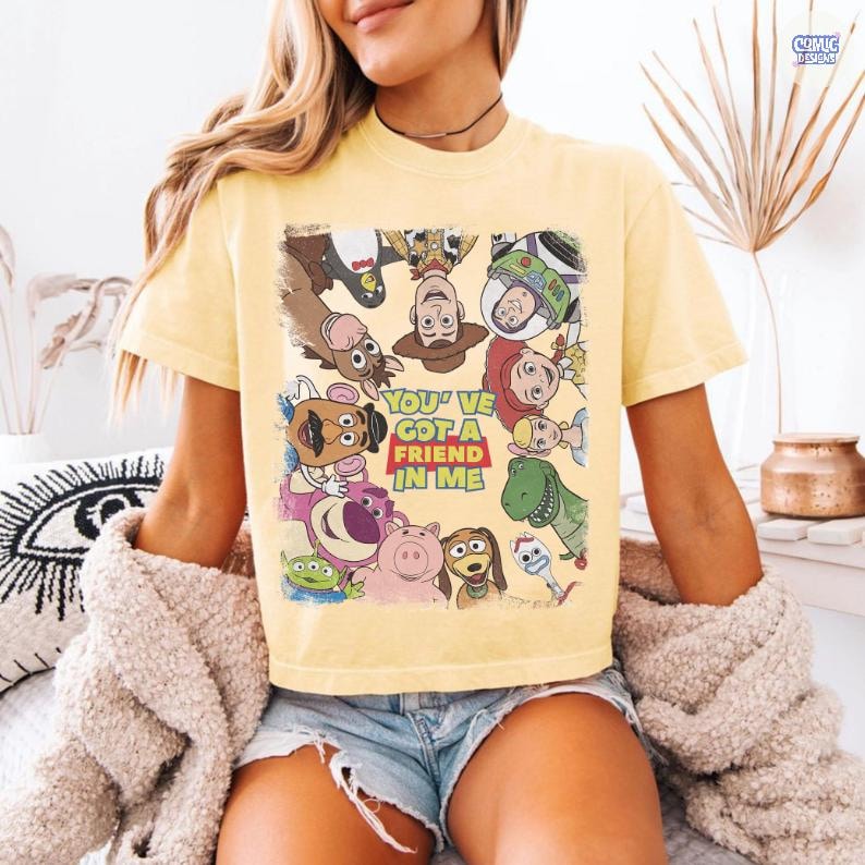 May include: Yellow t-shirt featuring a graphic of characters from the animated film Toy Story. The shirt includes the phrase "You've Got a Friend in Me" in a red and yellow box. The shirt is short-sleeved.