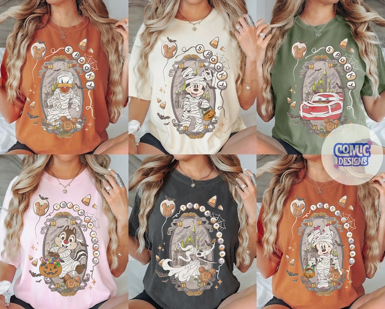 Puede incluir: Una colecci&oacute;n de seis camisetas de manga corta en varios colores, cada una con un estampado gr&aacute;fico de un personaje de dibujos animados con disfraz de Halloween, incluyendo momias y un coche de carreras, rodeados de dulces y calabazas.