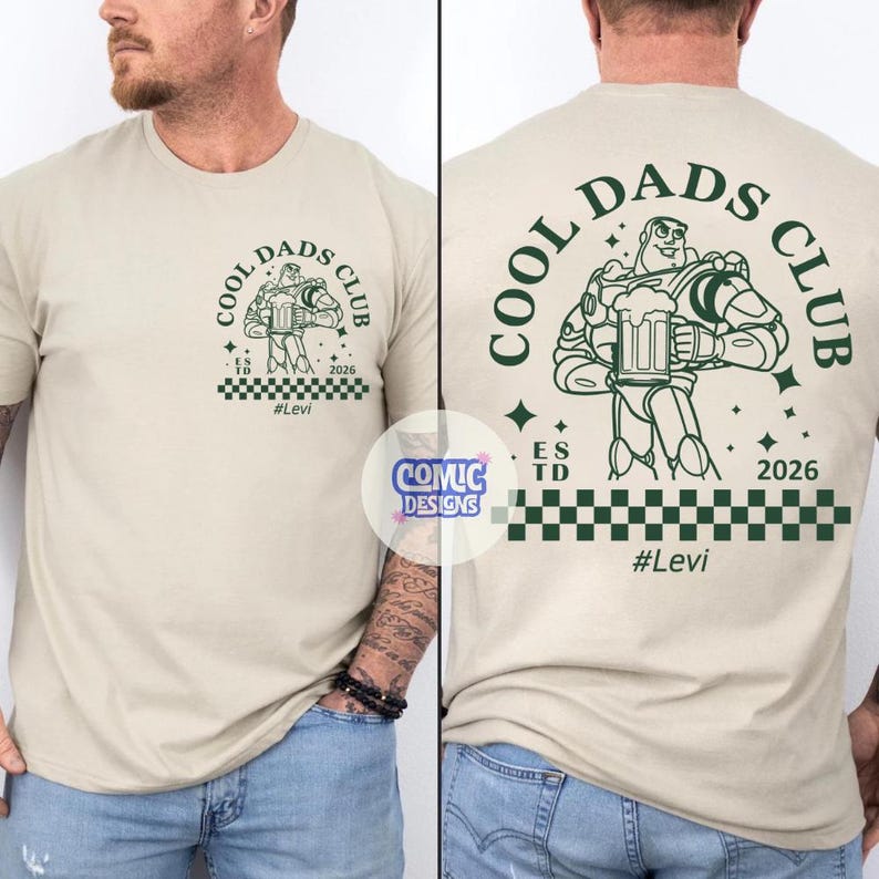 May include: Beige t-shirt with a green graphic of Buzz Lightyear holding a beer mug, with the text "COOL DADS CLUB" and "#Levi". The shirt has a checkered pattern at the bottom and the year "2026".
