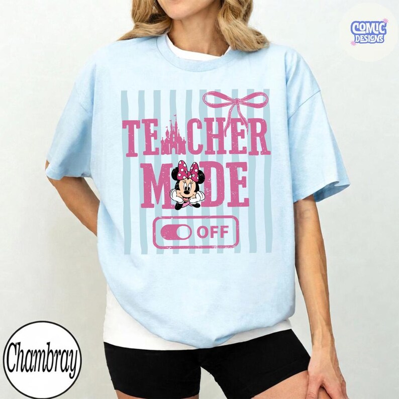 May include: Light blue t-shirt with the text "TEACHER MODE OFF" in pink, featuring a Minnie Mouse graphic. The design includes a castle silhouette and a bow. The shirt has vertical light blue stripes.