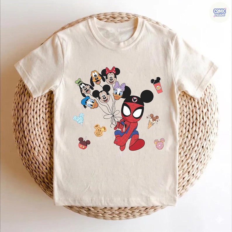 Peut inclure: T-shirt cr&egrave;me avec un personnage de dessin anim&eacute; Spider-Man avec des oreilles de Mickey Mouse, tenant des ballons avec des personnages Disney. Graphiques Disney suppl&eacute;mentaires, dont des glaces, des beignets et des t&ecirc;tes de Mickey Mouse.