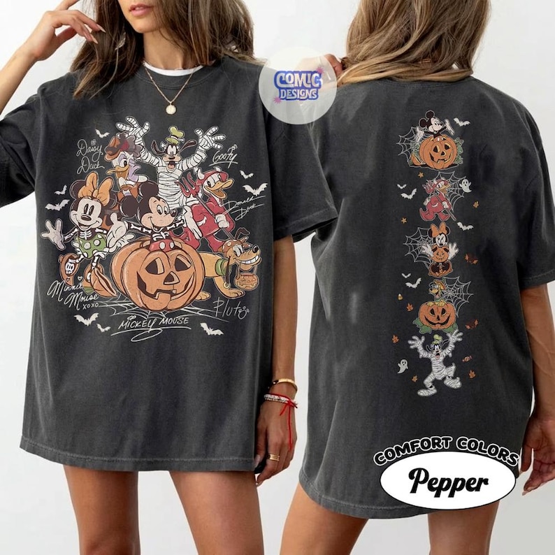 Op de afbeelding: Een antracietgrijs oversized T-shirt met een afbeelding op de voorkant van Disney-figuren in Halloween-kostuums rond een pompoen, inclusief de tekst Mickey Mouse en Pluto. De achterkant toont een verticale kolom van figuren en pompoenen.