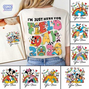 K&ouml;nnte beinhalten: Cremefarbenes T-Shirt mit dem Text "I'M JUST HERE FOR FIELD DAY 2023" in bunten Buchstaben. Das Shirt zeigt verschiedene Disney-Charaktere. Zus&auml;tzliche Designs umfassen einzelne Charaktergrafiken mit Regenbogen und dem Text "Your Name".