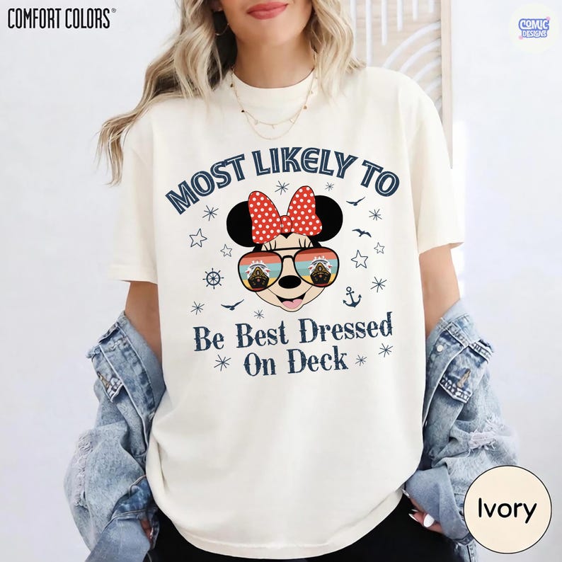 May include: Ivory-colored t-shirt with the text "MOST LIKELY TO Be Best Dressed On Deck" and a Minnie Mouse graphic wearing sunglasses. The shirt has a relaxed fit and is made of a soft material. The Comfort Colors brand is visible.