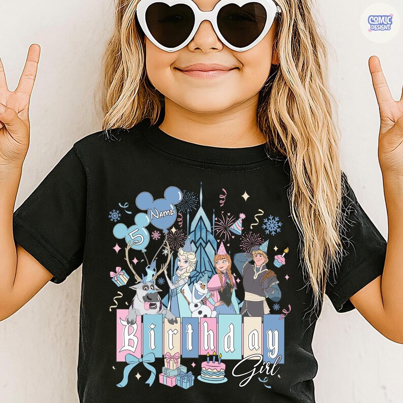 May include: Black t-shirt featuring a colorful graphic of characters from a popular animated movie, including a castle, reindeer, and the text "Birthday Girl." The design includes balloons, presents, and a birthday cake. The number "5" is also displayed.