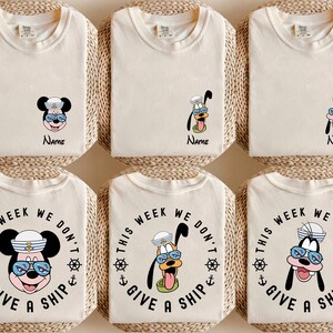 May include: Six cream-colored t-shirts with cartoon character designs. Three shirts feature a character with the name "Name" below. The other three shirts have the text "THIS WEEK WE DON'T GIVE A SHIP" around a character.
