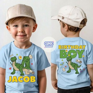Puede incluir: Camiseta azul claro con un dise&ntilde;o de dinosaurio y el nombre "JACOB". La parte delantera presenta un dinosaurio verde, el n&uacute;mero 4 y otros elementos l&uacute;dicos. La parte trasera dice "BIRTHDAY BOY".