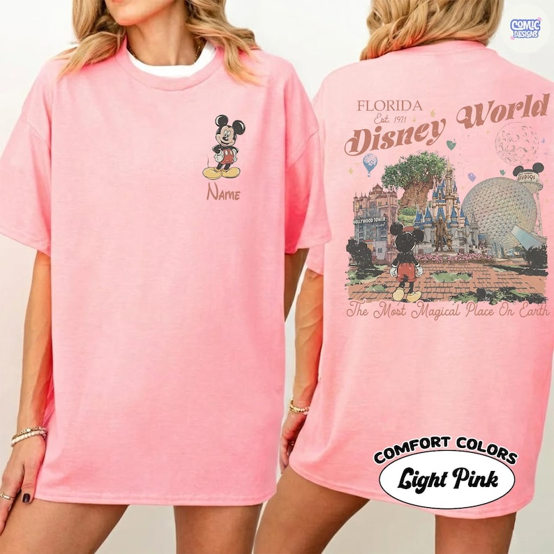K&ouml;nnte beinhalten: Hellrosa T-Shirt mit Mickey Mouse auf der Vorderseite und einem Namensfeld. Auf der R&uuml;ckseite des Shirts befindet sich ein Disney World-Motiv mit dem Text "Florida Est. 1971 Disney World" und "The Most Magical Place On Earth".
