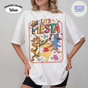 May include: White t-shirt with a colorful "Let's Fiesta" graphic featuring cartoon characters wearing sombreros and playing maracas. The shirt has the "Comfort Colors" and "Comic Designs" logos.
