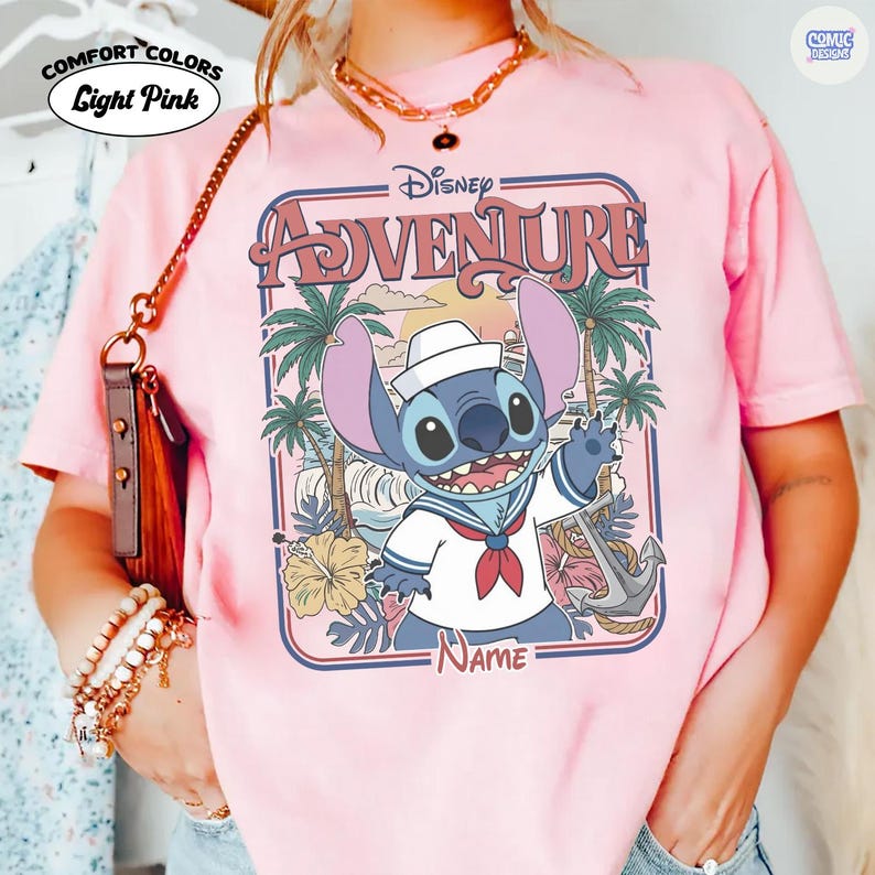 Op de afbeelding: Lichtroze Comfort Colors T-shirt met een Disney Adventure ontwerp. De afbeelding toont Stitch in een matrozenoutfit, palmbomen en een anker. Het woord "Adventure" staat in een retro lettertype, met het Disney logo bovenaan.