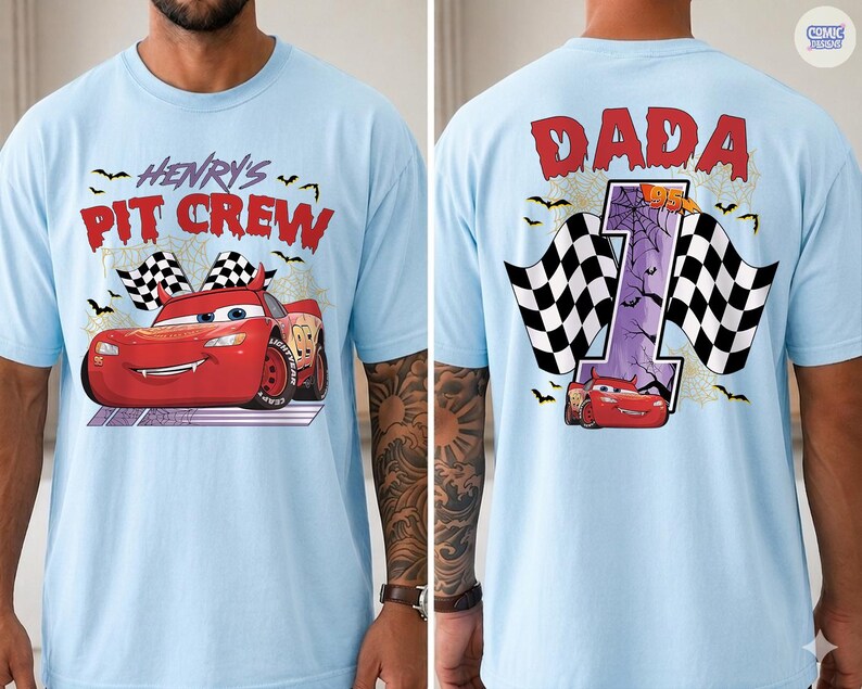 Puede incluir: Una camiseta azul claro con un gr&aacute;fico de coche de carreras rojo. El frente muestra el texto "HENRY'S PIT CREW" con banderas a cuadros y murci&eacute;lagos. La parte posterior muestra el texto "DADA" sobre un n&uacute;mero "1" grande con telara&ntilde;as y un coche.