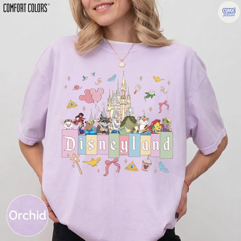 Pu&ograve; includere: T-shirt color orchidea con grafica Disneyland. Il design presenta un castello, personaggi dei cartoni animati e la scritta "Disneyland" in un font pastello. La maglietta ha maniche corte e una vestibilit&agrave; rilassata. Il marchio "COMFORT COLORS" &egrave; stampato in alto a sinistra.