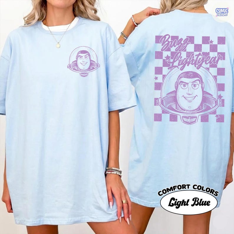 Puede incluir: Camiseta azul claro con Buzz Lightyear de Toy Story. La parte delantera tiene un peque&ntilde;o gr&aacute;fico de Buzz, mientras que la parte trasera muestra un dise&ntilde;o m&aacute;s grande con el texto "Buzz Lightyear" y un patr&oacute;n de cuadros. La camiseta est&aacute; etiquetada como "Comfort Colors" y "Light Blue".