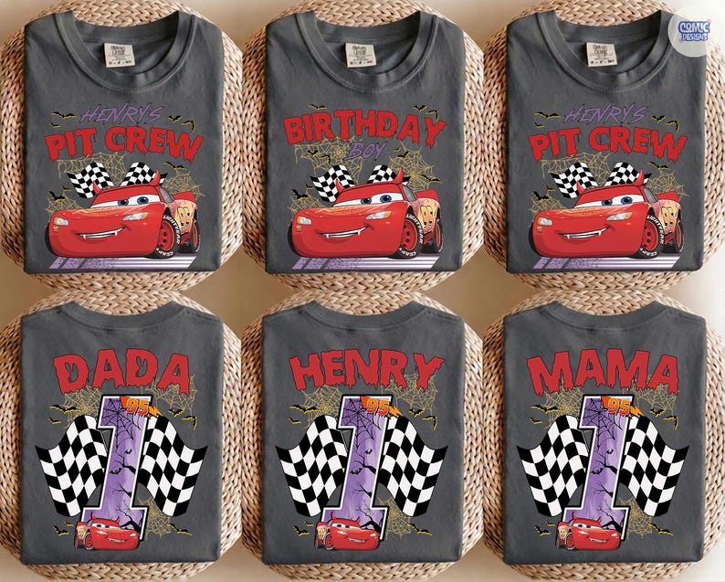 Puede incluir: Una colecci&oacute;n de seis camisetas gris oscuro con estampados gr&aacute;ficos de un coche de carreras rojo, banderas a cuadros, telara&ntilde;as y murci&eacute;lagos. Las camisetas muestran textos como Henry's Pit Crew, Birthday Boy, Dada, Henry y Mama, junto con el n&uacute;mero 1.
