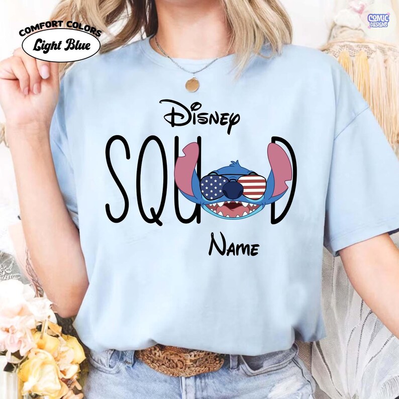 May include: Light blue t-shirt with the word "SQUAD" in black, featuring a Disney Stitch graphic wearing sunglasses with American flag designs. The word "Disney" is above the graphic, and "Name" is below.
