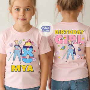 Puede incluir: Camiseta rosa claro con un dibujo animado de un personaje con un bast&oacute;n, el n&uacute;mero 8 y el nombre "MYA". La parte trasera de la camiseta dice "BIRTHDAY GIRL". La camiseta tiene cuello redondo y mangas cortas.
