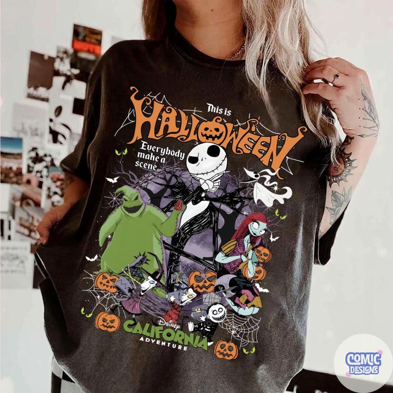 May include: Dark gray t-shirt featuring a graphic from "The Nightmare Before Christmas." The design includes Jack Skellington, Sally, Oogie Boogie, and other characters, with the text "This is Halloween" and "California Adventure."