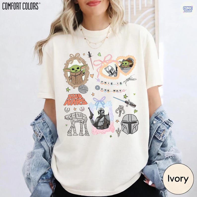 Puede incluir: Camiseta de color marfil con gr&aacute;ficos de Star Wars, incluyendo a Grogu, el Mandaloriano y otros s&iacute;mbolos. Se muestra el texto "THIS IS THE WAY". La camiseta es de la marca Comfort Colors.
