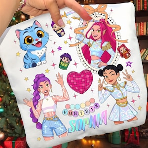 May include: White pillow with colorful cartoon graphics. Features a blue cat, portraits of women, a disco heart, and the text "HUNTRIX SOPHIA". Decorated with stars and other illustrations.