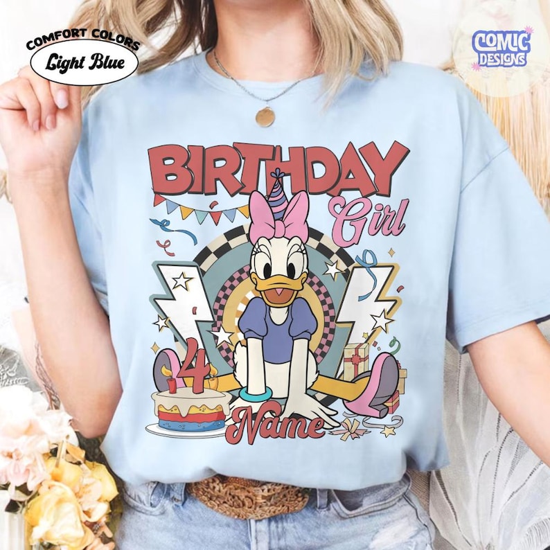 May include: Light blue Comfort Colors t-shirt with a Daisy Duck graphic. The shirt features the text "BIRTHDAY Girl" and "4" with a cake, and "Name" in a script font. The design includes stars, lightning bolts, and gift boxes.