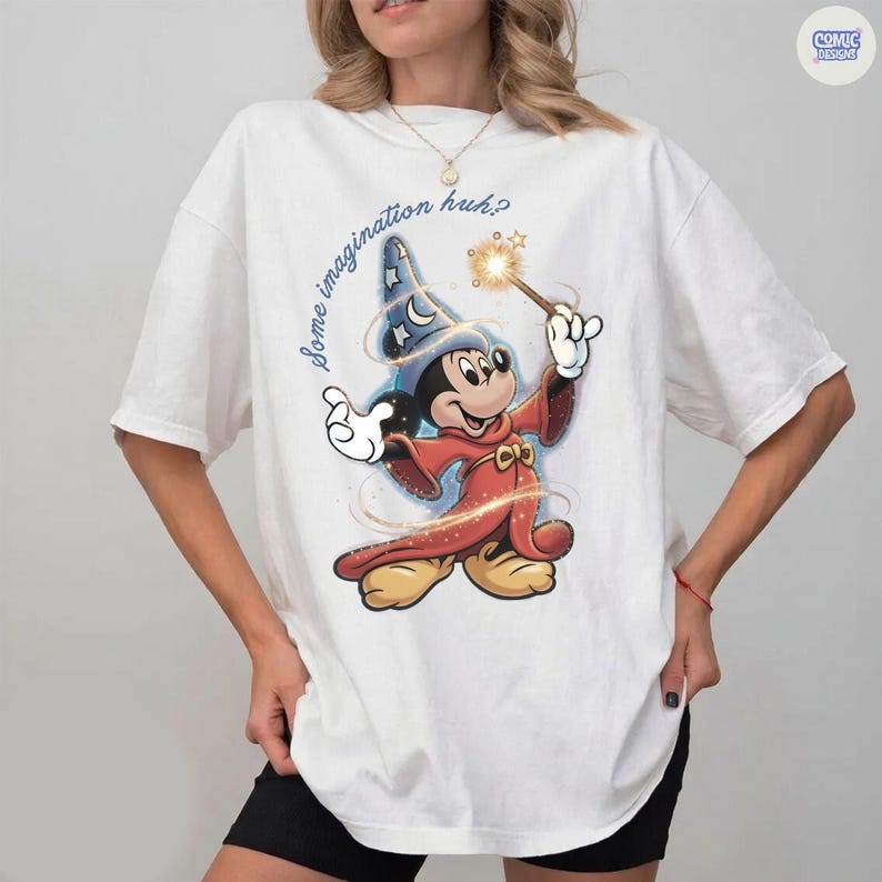 May include: White t-shirt with a cartoon Mickey Mouse wizard design, holding a wand with a sparkling effect. The text "Some imagination huh?" is above the character. The shirt has a Comic Designs logo.