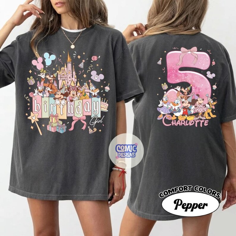 May include: Dark grey t-shirt featuring a colorful birthday design with Disney characters, a castle, and the text "Birthday Girl" on the front. The back of the shirt displays a large pink number 5 with Disney characters and the name "Charlotte".