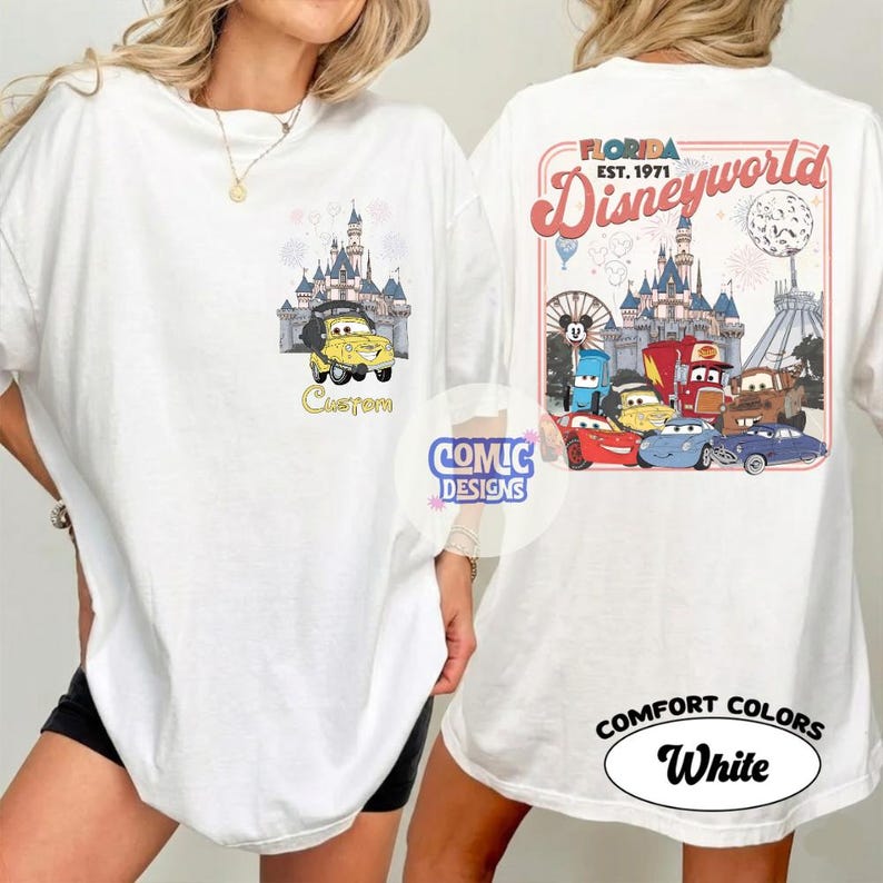 K&ouml;nnte beinhalten: Wei&szlig;es T-Shirt mit einem gelben Cartoon-Auto vor einem Schloss und dem Wort "Custom". Auf der R&uuml;ckseite befindet sich ein "Florida Disneyworld"-Design mit Cartoon-Autos und einem Schloss. Das Shirt hat auch die Worte "Comfort Colors" und "White".