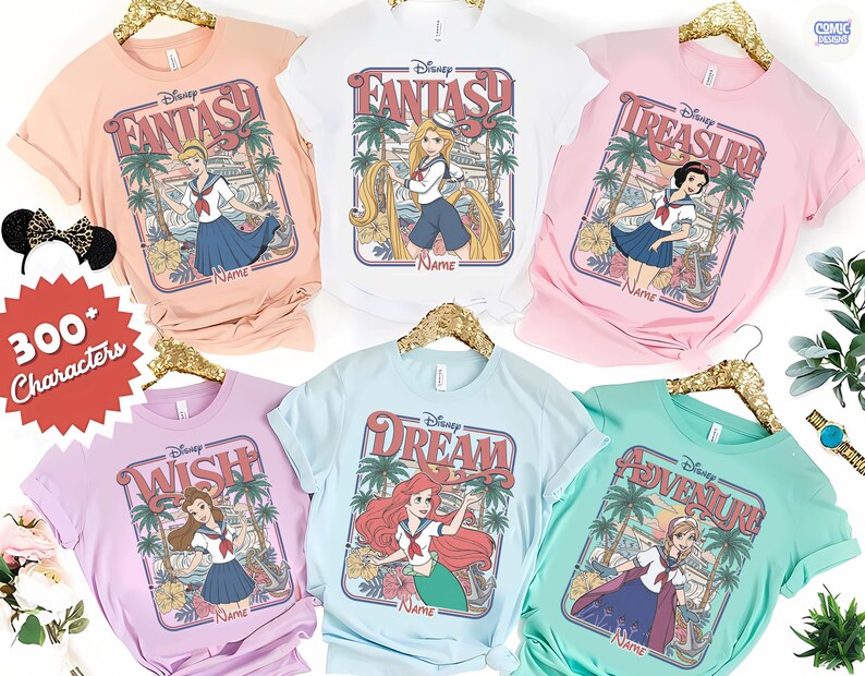 Op de afbeelding: Een verzameling pastelkleurige t-shirts met Disney-prinsessenontwerpen. Elk shirt toont een prinsessenillustratie in een rechthoekige lijst met de woorden "Fantasy", "Treasure", "Wish", "Dream" en "Adventure".