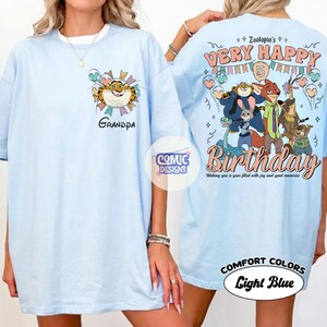 Puede incluir: Camiseta azul claro con un tigre de dibujos animados y la palabra "Grandpa" en la parte delantera. La parte trasera muestra "Zootopia's Very Happy Birthday" con personajes de dibujos animados y el texto "Wishing you a year filled with joy and good memories."