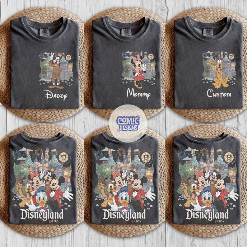May include: A collection of six charcoal gray t-shirts featuring Disney character graphics. The top row displays individual characters with text reading Daddy, Mommy, and Custom. The bottom row shows a group scene with the text Disneyland.
