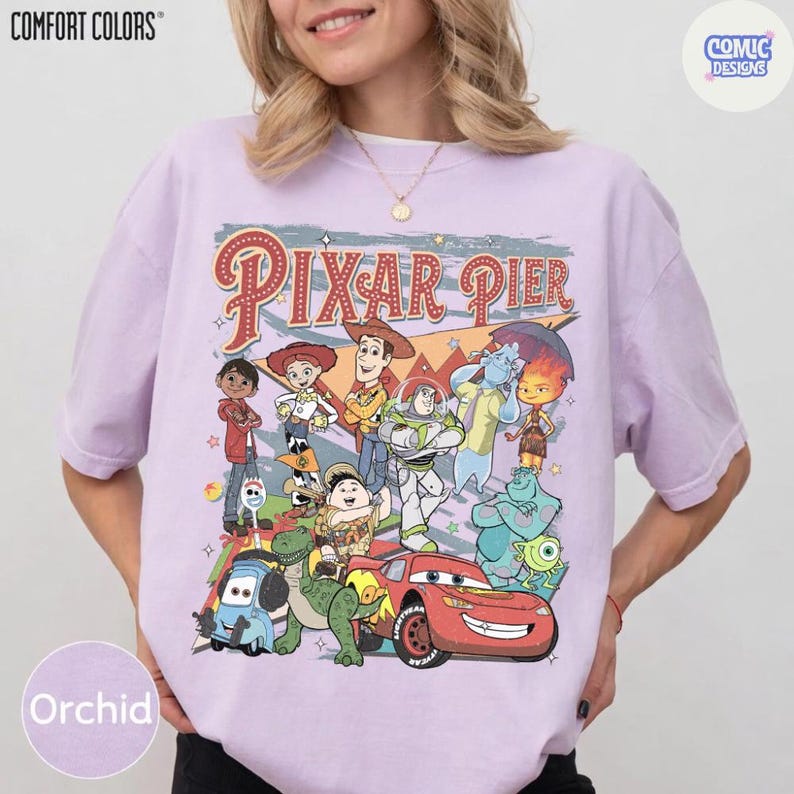 Pu&ograve; includere: T-shirt color orchidea con una grafica con le parole "Pixar Pier" e vari personaggi animati. La maglietta ha maniche corte e girocollo. Il marchio "Comfort Colors" &egrave; stampato in alto a sinistra.