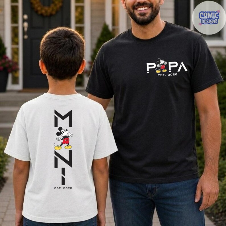 May include: Two t-shirts, one black and one white, featuring Mickey Mouse graphics. The black shirt says "PAPA EST. 2026" with a Mickey Mouse design. The white shirt has a Mickey Mouse design and the text "M-7-1 EST. 2026".